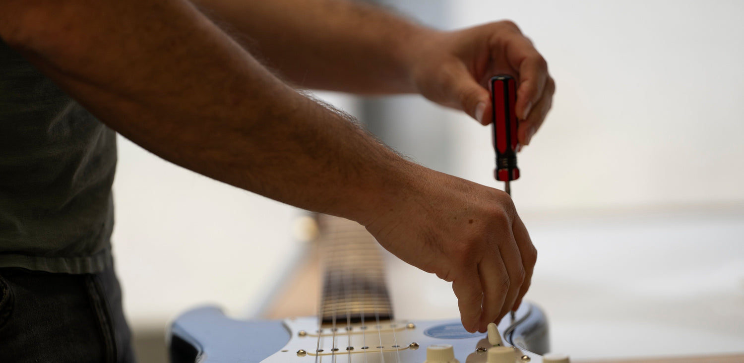 ObsidianWire loaded pickguard being installed in a black Fender Stratocaster guitar