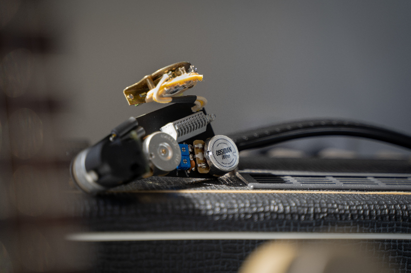 An obsidianwire Custom HH wiring harness for Stratocaster is artfully placed on top of an amplifier